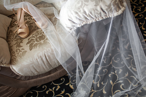 Wedding shoes with veil on vintage armchair.