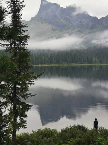 woman standing in front of mountain lake in mountains of Ergaki natural reserve, Russia.