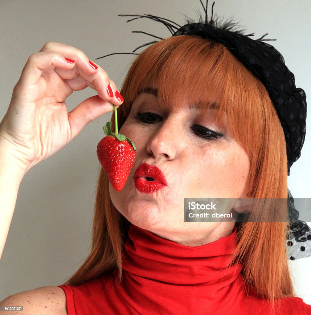 Strawberry Kiss Portrait of a beautiful woman, kissing a strawberry Adult Stock Photo