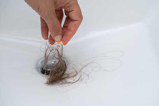 Female hairs in sink. Hair loss concept.