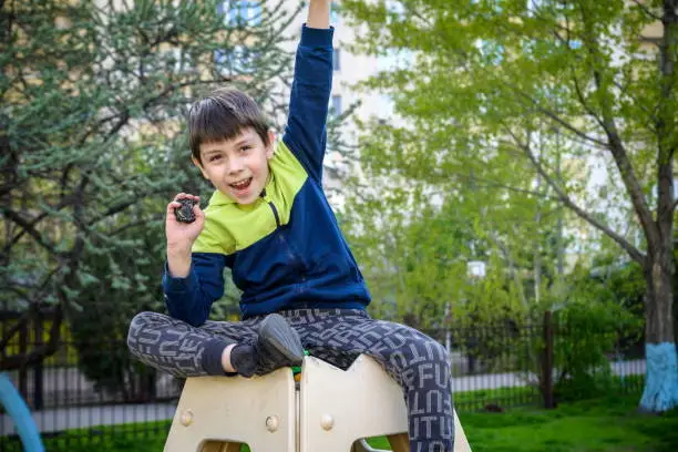 Photo of Boy playing with modern spin top outdoors. Entertainment game for children. Top, triggered by a trigger. Kid demonstrate two different variants choosing which is better