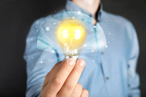 istock Glow up your ideas. Man holding light bulb on dark background, closeup 1412413414