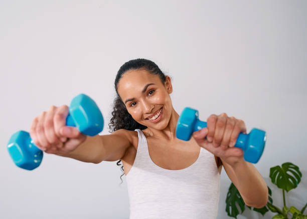 istock A young woman smiles while holding 2kg weights at home 1412413521