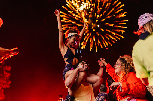 Carefree friends dancing on a music festival with the fireworks in the background