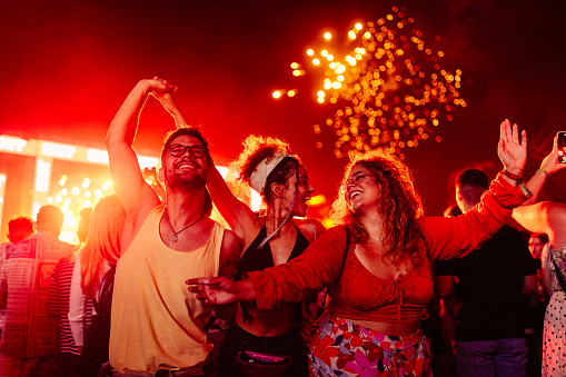Three party people at the music festival, enjoying performance and fireworks