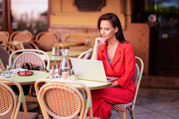 istock Thinking woman sitting at outdoor cafe and using her laptop 1412414088