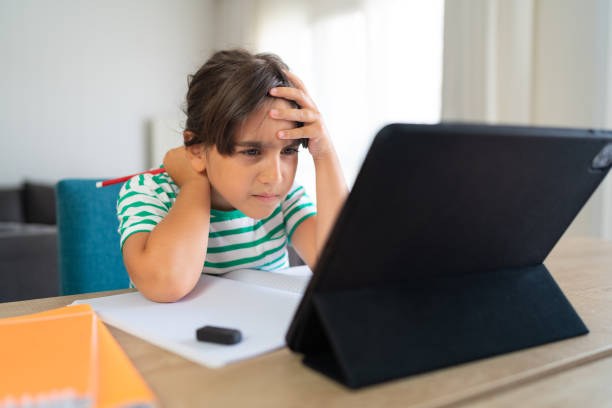 Child sitting alone at home and feeling stressed while doing her homework Child sitting alone at home and feeling stressed while doing her homework myopia stock pictures, royalty-free photos & images