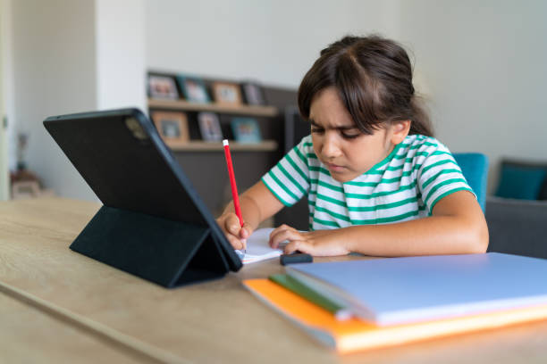 istock Child sitting alone at home and feeling stressed while doing her homework 1412415086