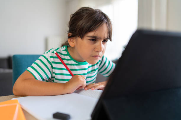 Child sitting alone at home and feeling stressed while doing her homework