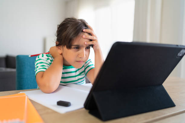 istock Child sitting alone at home and feeling stressed while doing her homework 1412415116