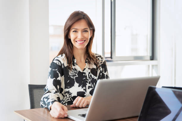 istock Confident middle aged businesswoman using laptop while working at the office 1412415214