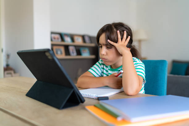 istock Child sitting alone at home and feeling stressed while doing her homework 1412415221