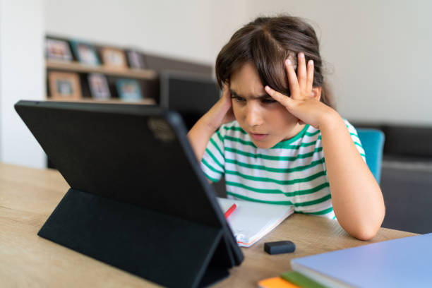istock Child sitting alone at home and feeling stressed while doing her homework 1412415227