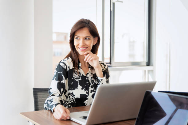 istock Confident middle aged businesswoman using laptop while working at the office 1412415235