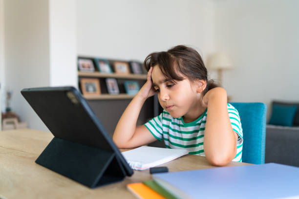 istock Child sitting alone at home and feeling stressed while doing her homework 1412415240