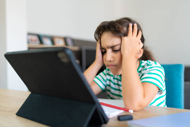 istock Child sitting alone at home and feeling stressed while doing her homework 1412415291