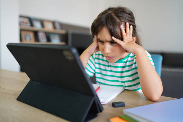 istock Child sitting alone at home and feeling stressed while doing her homework 1412415352