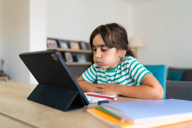 istock Child sitting alone at home and feeling stressed while doing her homework 1412415359