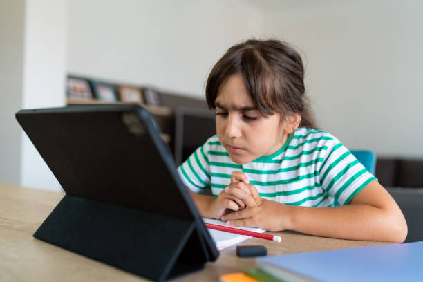 istock Child sitting alone at home and feeling stressed while doing her homework 1412415402