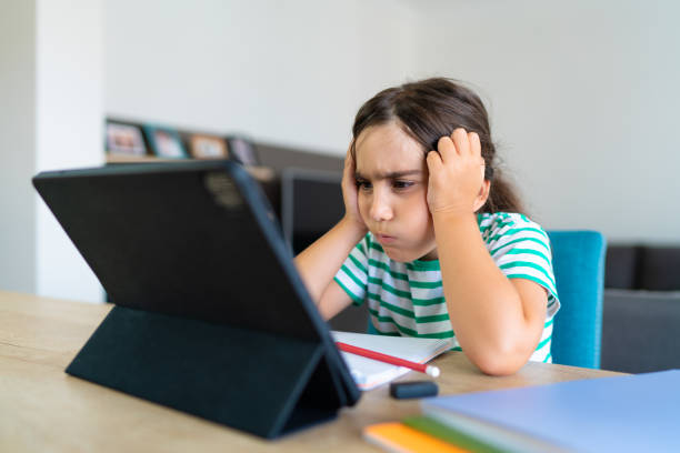 istock Child sitting alone at home and feeling stressed while doing her homework 1412415405