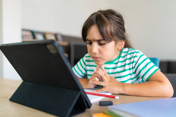 istock Child sitting alone at home and feeling stressed while doing her homework 1412415409
