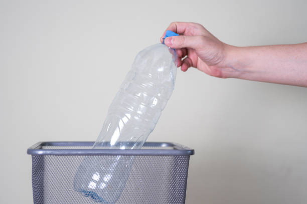 istock Throw a plastic bottle in the trash on a gray background. 1412415620
