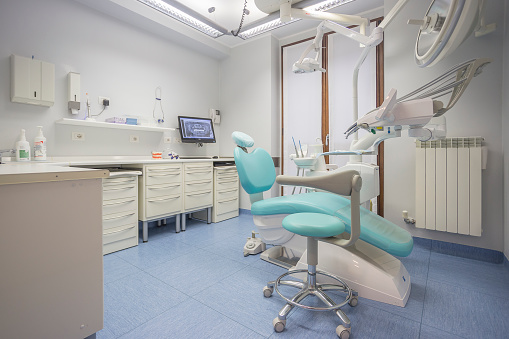 Interior shot of a dentist studio with a professional dentist chair, no people are visible.