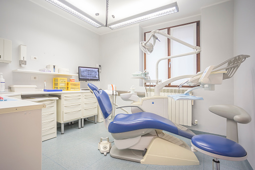 Interior shot of a dentist studio with a professional dentist chair, no people are visible.