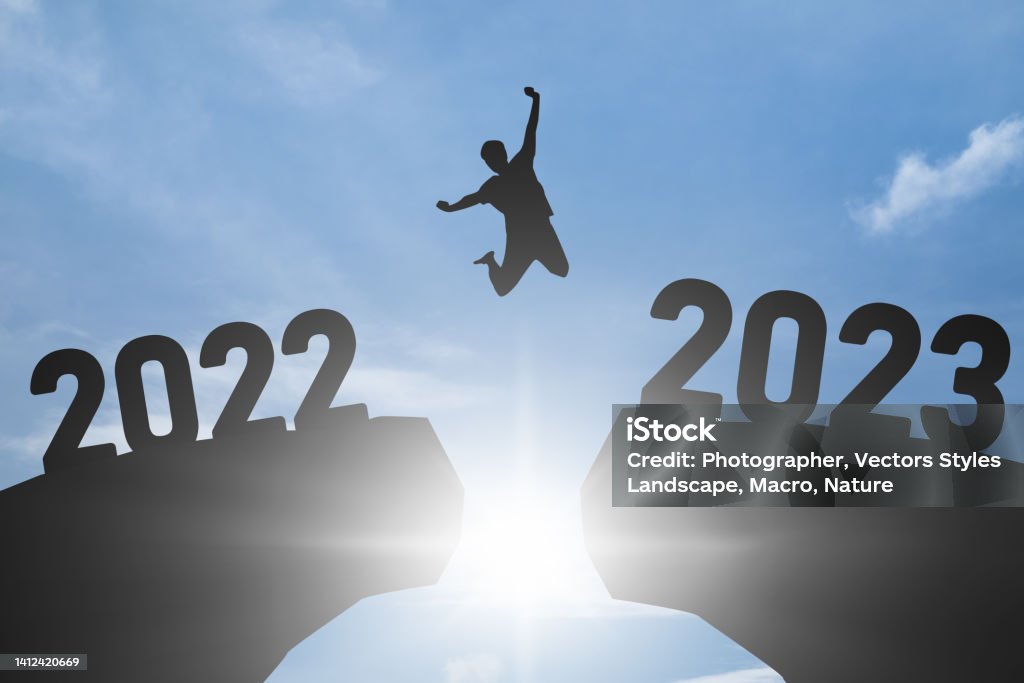 Concept Happy new year 2023 Silhouette image of happy man jump from 2022 up to 2023 on blue sky background. 2023 Stock Photo