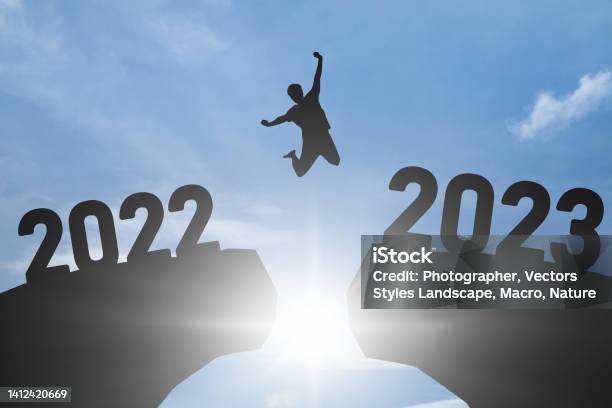 Concept Happy New Year 2023 Silhouette Image Of Happy Man Jump From 2022 Up To 2023 On Blue Sky Background Stock Photo - Download Image Now