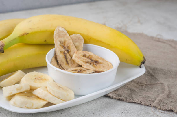 istock Banana and dried banana chips scattered on grey background. 1412421164