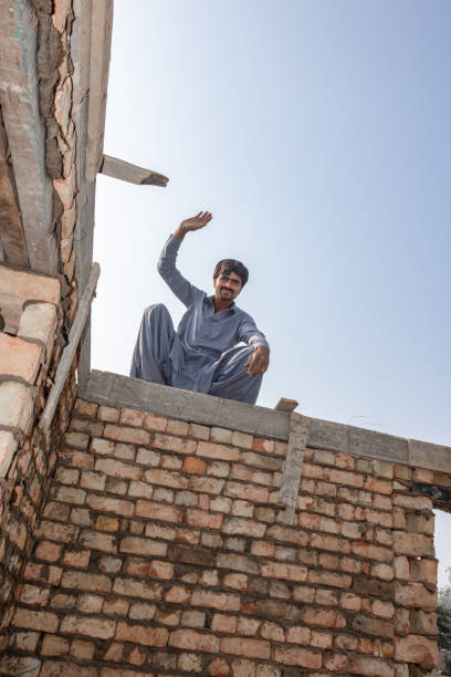 joven albañil levantando la mano durante el trabajo - mason brick bricklayer installing fotografías e imágenes de stock