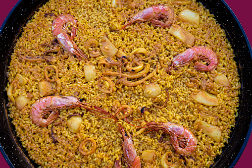 Seafood Paella recipe with rice, cuttlefish, shrimp and squid Spain recipe from Valencia on the pan called paellera