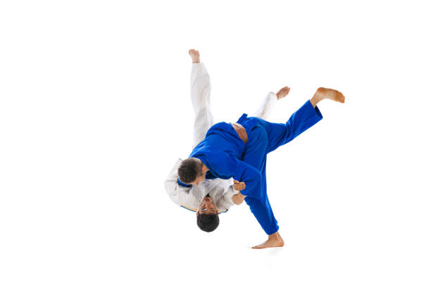 Studio shot of two men, professional judo athletes training isolated over white background