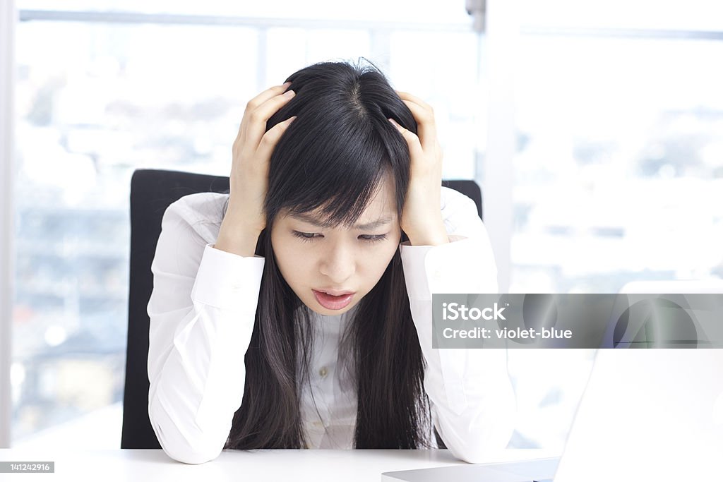business woman holding her head young business woman holding her head at her office Head In Hands Stock Photo