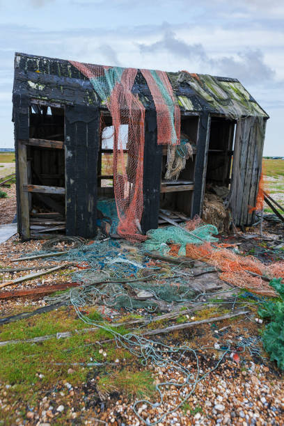 Discarded fishing nets draped over the remains of an old derelict fisherman's shack  at Dungeness, Kent, UK