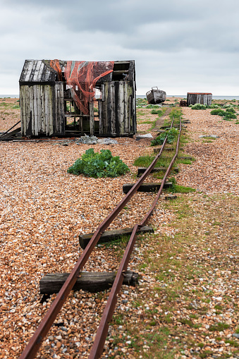 Ruined and derelict old fisherman's hut, rusting trackway and an abandoned old fishing boat on the shingle beach at Dungeness in Kent.  Dungeness is one of the largest expanses of shingle in Europe.