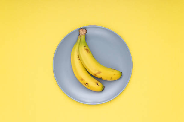 istock 2 bananas on a gray plate. yellow background 1412430930