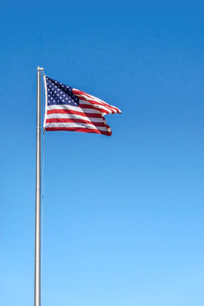 istock American Flag Waving In Wind Against a Deep Blue Sky 1412431639
