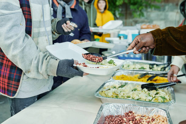 voluntarios alimentando a personas sin hogar al aire libre - homelessness men white black fotografías e imágenes de stock