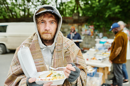 Hombre sin hogar comiendo comida al aire libre photo