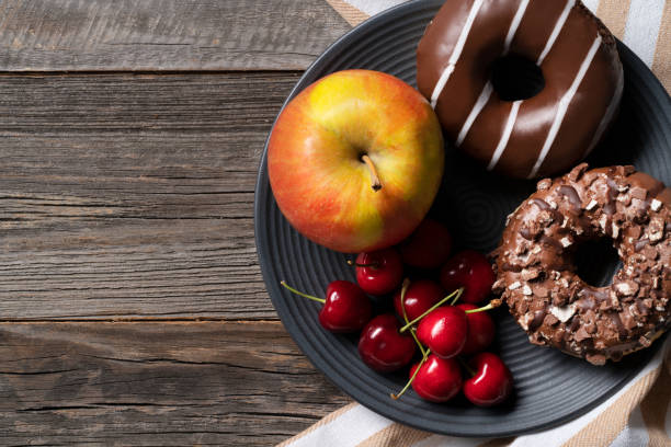 istock Freshly baked glazed donuts exposed on decorative platter with cherries and apple on the side. 1412434178