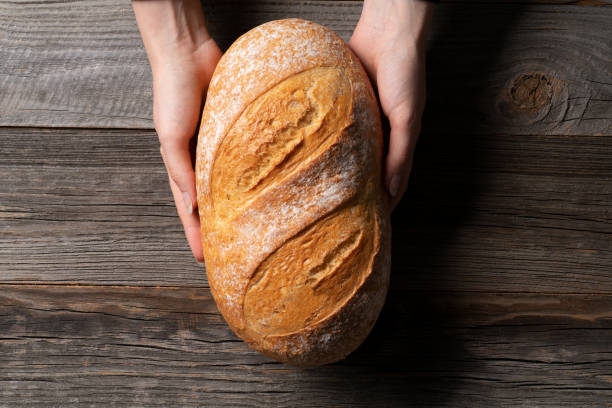 istock Lady baker is holding freshly baked white bread 1412434394