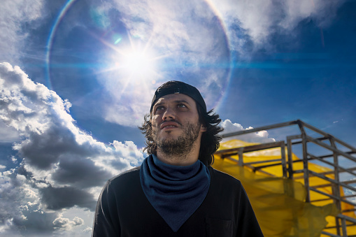 Caucasian working man  with a blue scarf and black t-shirt  against the sunny  sky