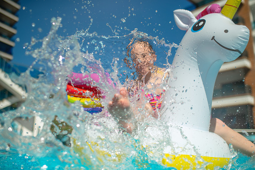Child with inflatable raft unicorn on summer vacations