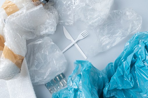 Top view of crossed plastic cutlery surrounded by plastic garbage.