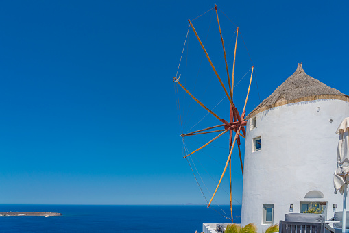 View of a mill in Oia on Santorini island, Greece, background the blue sea