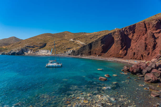 wunderschöne landschaft des roten sandstrandes mit einem boot im dorf akrotiri auf santorini - black sand beach santorini greece stock-fotos und bilder
