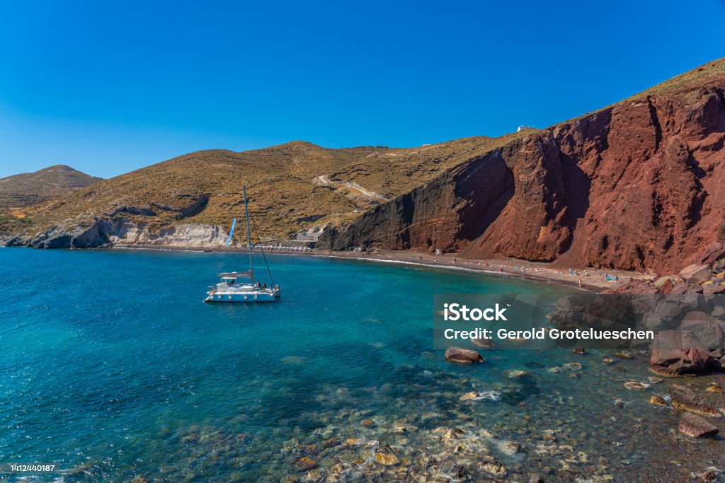 Beautiful scenery of red sand beach with a boat in Akrotiri village on Santorini Beautiful scenery of red sand beach with a boat in Akrotiri village on Santorini, Greece Greece Stock Photo