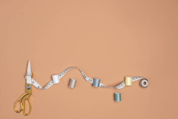 Scissors, measuring tape and spools of thread aranged on the
